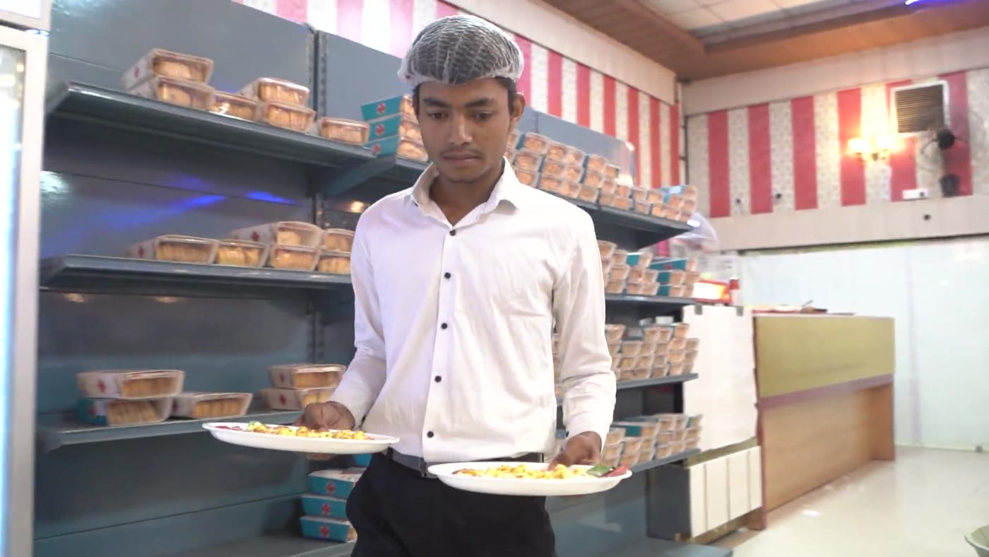 Server carrying pure vegetarian plates during a function at Maa Mahal