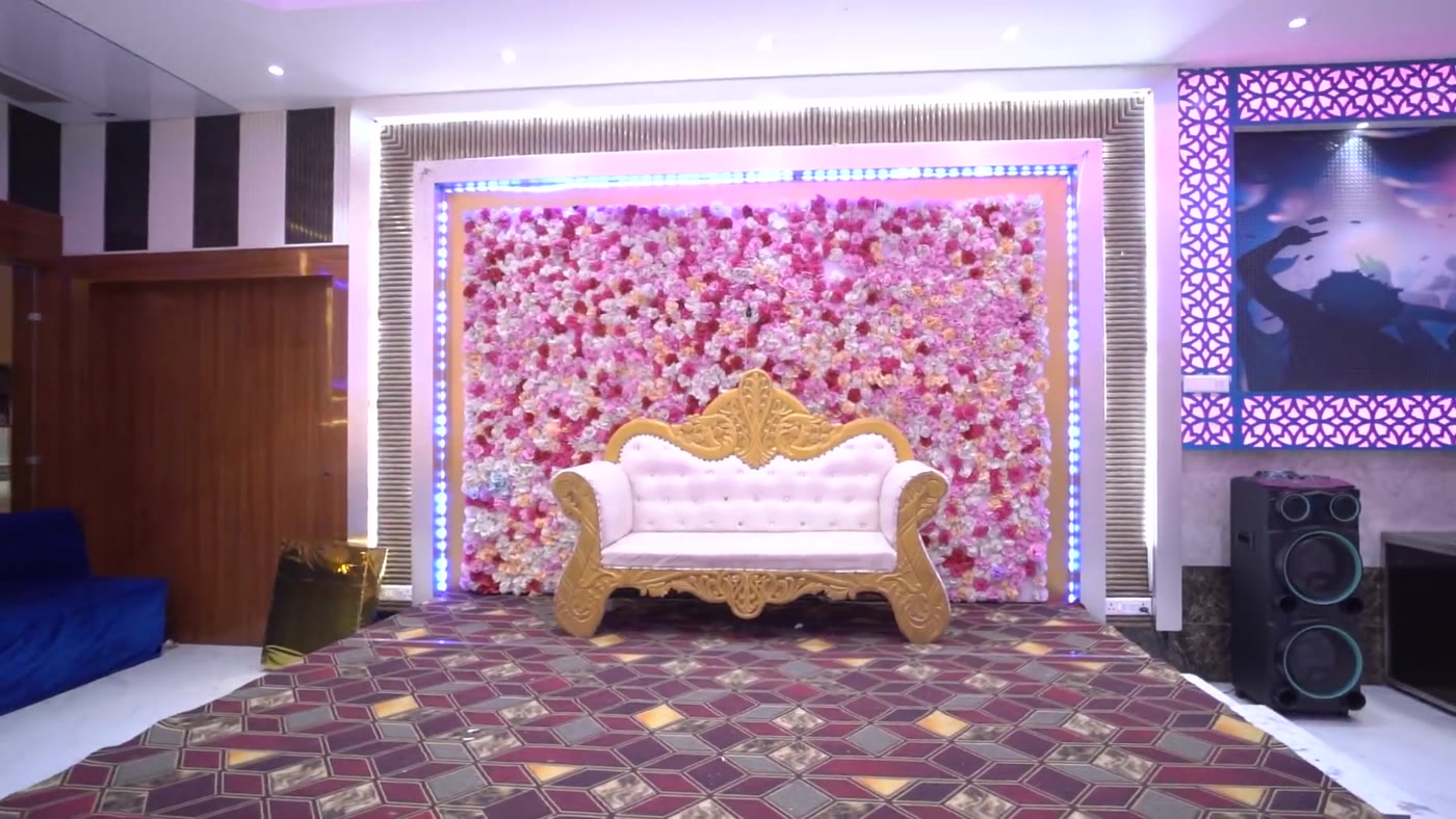 Reception stage with floral backdrop and seating inside the party hall
