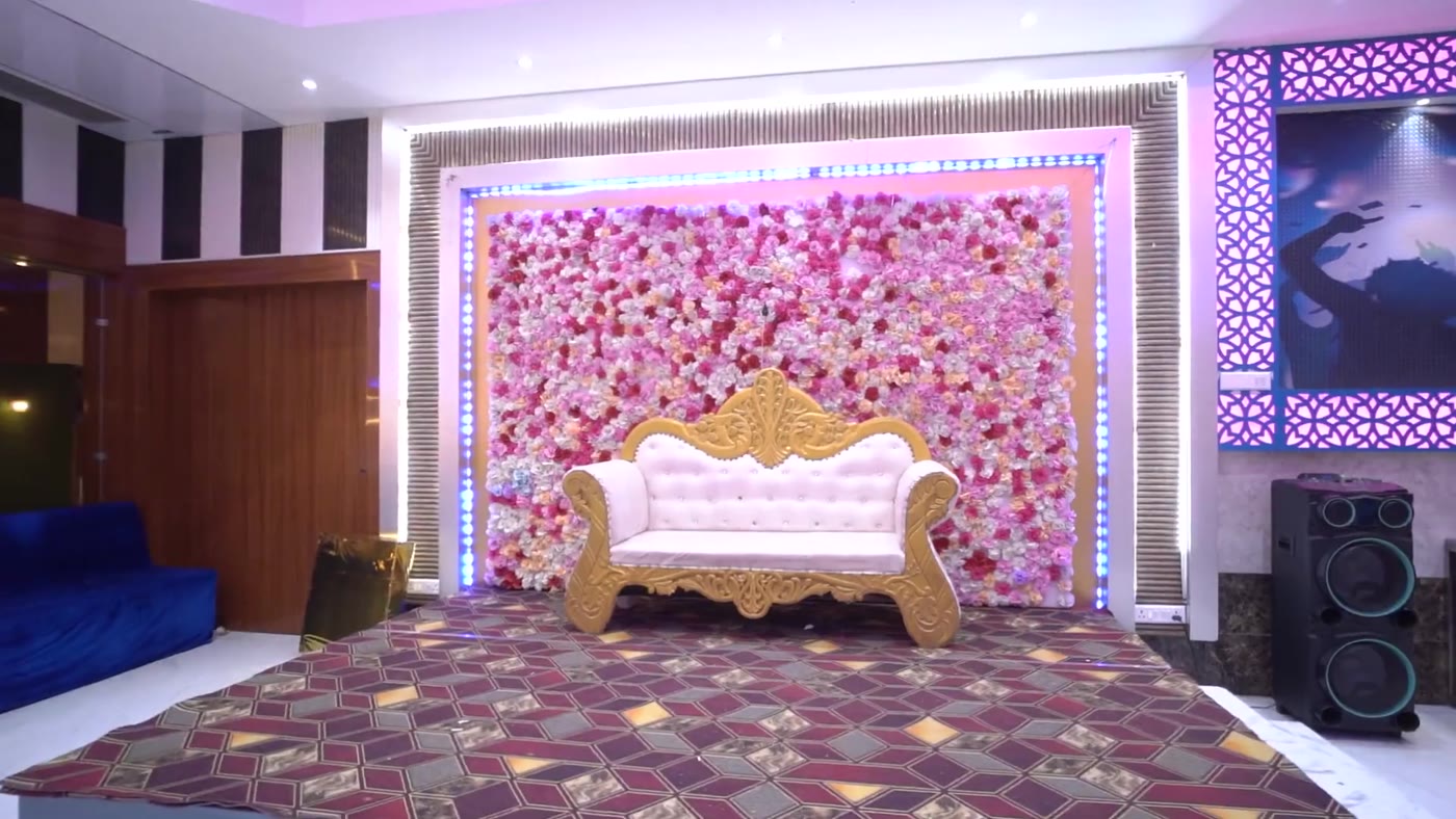 Wedding stage with pink floral backdrop and gold sofa inside Hall 1